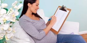 pregnant-woman-sitting-in-a-chair-writing-baby-names-picture-id177125958.jpg