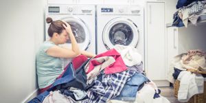 unhappy-stressed-woman-with-pile-of-clothes-near-washing-machine-in-picture-id1170069046.jpg