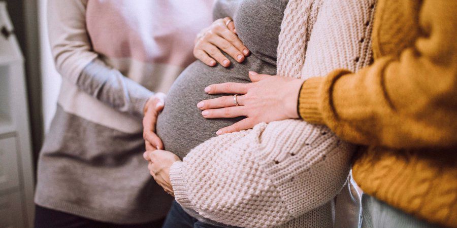 friends touching pregnant baby bump