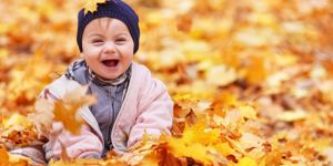 baby playing in fall autumn leaves