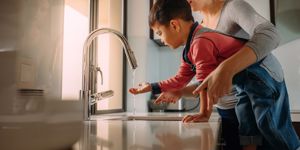 mom with child washing hands in sink