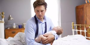 stressed-father-dressed-for-work-holding-baby-in-bedroom-picture-id473423618.jpg