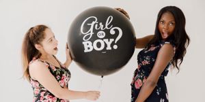 two mums holding gender reveal balloon