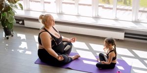 plus-size mum and daughter doing yoga together