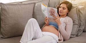 Pregnant woman and partner reading book.