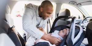 A dad puts his baby in the car seat