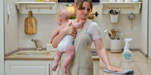 mum cleaning kitchen while holding baby