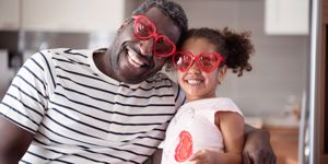 Dad and daughter smiling with valentine's glasses on