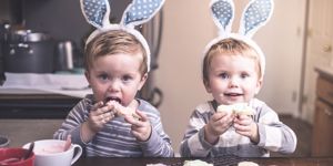 two toddlers wearing easter bunny ears and eating cake