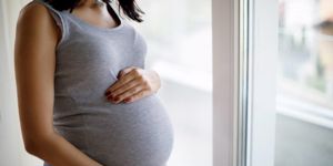 pregnant woman standing by window 