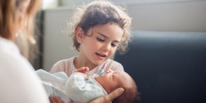 Young girl holds her newborn sibling