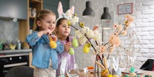 two young girls wearing easter bunny ears decorating in the house for easter
