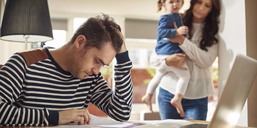 dad stressed with work while mum and child stands beside him