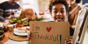 kid holding up thankful sign
