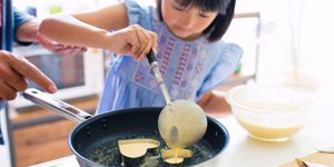 little girl making pancakes with mom