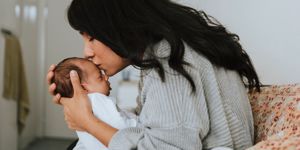 woman kissing newborn baby's had