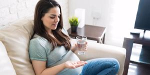 pretty-pregnant-woman-with-salad-in-bowl-on-sofa-picture-id1184284805.jpg