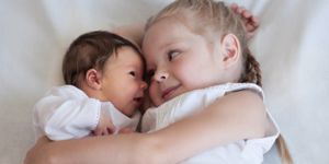 toddler cuddling with newborn baby sibling