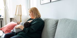 mother-using-mobile-phone-while-breastfeeding-baby-picture-id1254725504.jpg