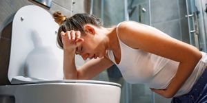 mom suffering with morning sickness over toilet