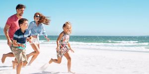 happy-family-running-on-beach-picture-id1137373430.jpg