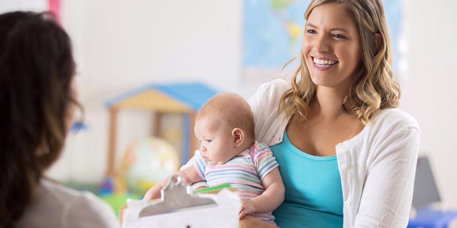 mom giving baby to preschool teacher