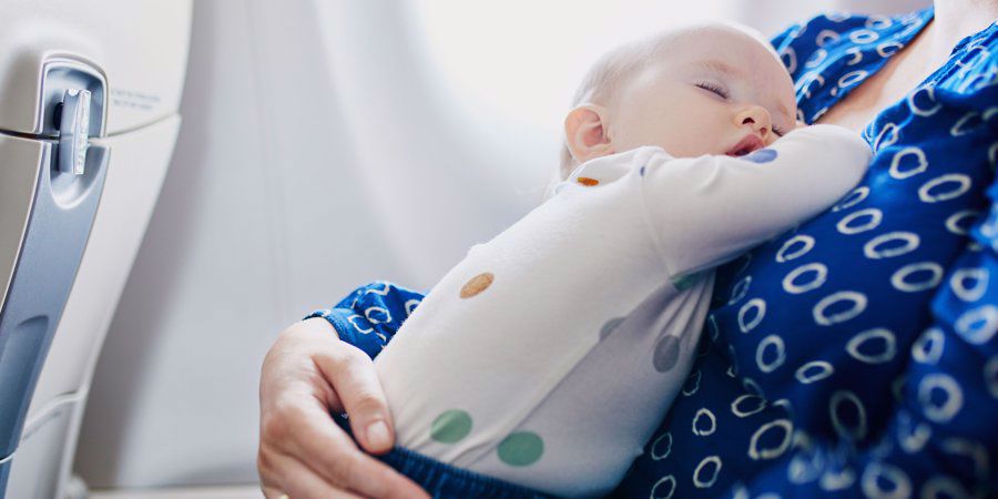 baby asleep on mother aboard a plane