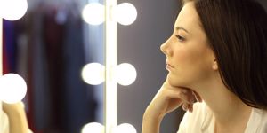 serious-woman-looking-at-make-up-mirror-picture-id811370250.jpg
