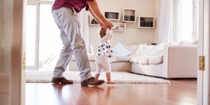 father-helping-daughter-learn-to-walk-at-home-side-view-picture-id947853502.jpg