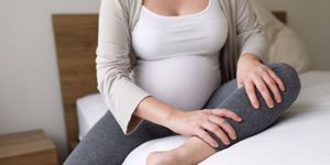 pregnant mom massaging leg on bed