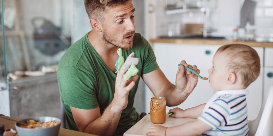 dad distracting baby to spoonfeed