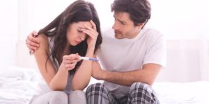 upset-man-comforting-his-depressed-wife-with-negative-pregnancy-test-picture-id1182426587.jpg
