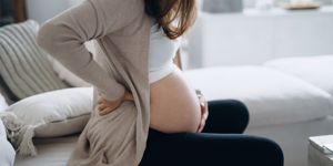 pregnant mom sat on couch holding large bump